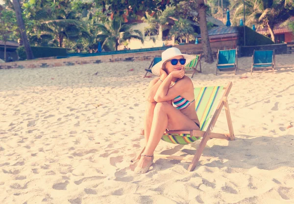 Frau mit Hut am Strand, im Liegestuhl sitzend und beobachtend — Stockfoto