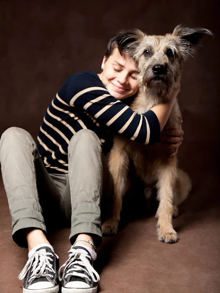 Mulher bonita com um cão desgrenhado engraçado em um backgrou escuro — Fotografia de Stock