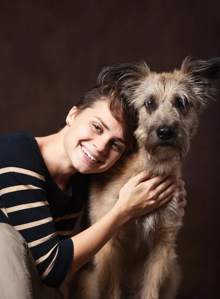 Mulher bonita com um cão desgrenhado engraçado em um backgrou escuro — Fotografia de Stock
