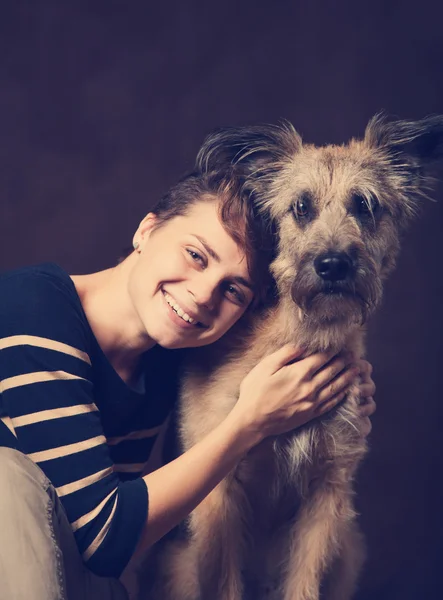 Beautiful young woman with a funny shaggy dog on a dark backgrou — Stock Photo, Image