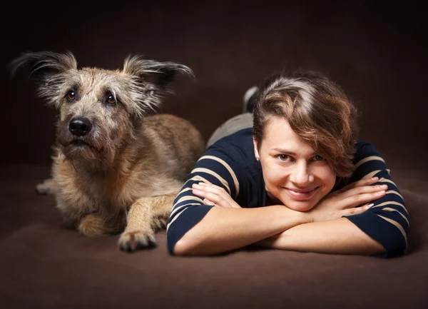 Mulher bonita com um cão desgrenhado engraçado em um backgrou escuro — Fotografia de Stock