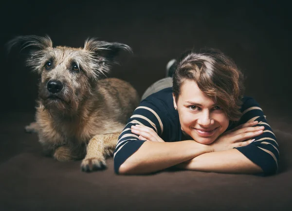 Mulher bonita com um cão desgrenhado engraçado em um backgrou escuro — Fotografia de Stock