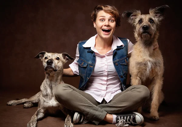 Mulher bonita com dois cães engraçados em um fundo escuro . — Fotografia de Stock