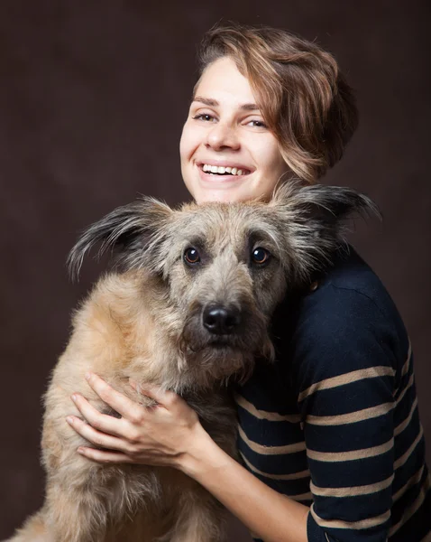 Mulher bonita com um cão desgrenhado engraçado em um backgrou escuro — Fotografia de Stock