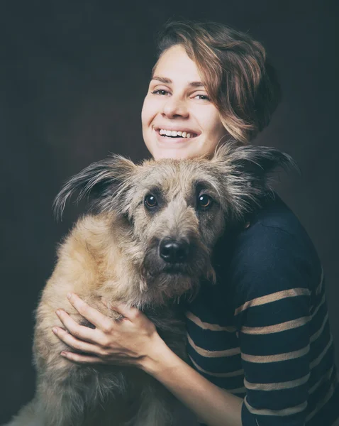 Mulher bonita com um cão desgrenhado engraçado em um backgrou escuro — Fotografia de Stock