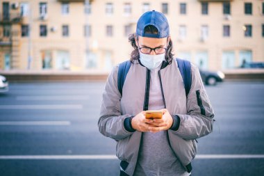Gözlüklü, koruyucu maskeli, sırt çantalı yakışıklı esmer hippi. Akıllı telefonlu bir adam. Salgın hastalıklı, normal bir yaşam tarzı.
