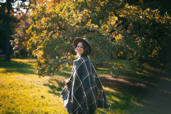 帽子の秋の公園で美しい巻き若い女性の肖像と自然を楽しむ遊び心のあるスカーフ歩く — ストック写真