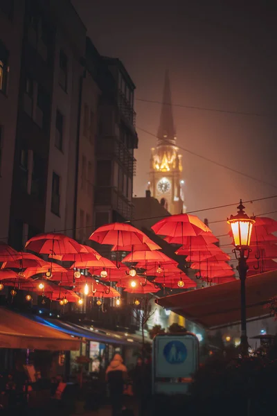 ノヴィ サド中心部の歩行者天国の通り古代の大聖堂の夜の街並みを見下ろす赤い傘で飾られた悲しい — ストック写真