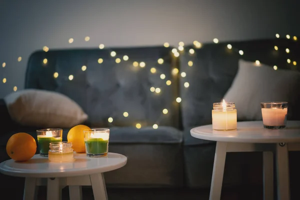 Velas e guirlandas em um sofá cinza na sala de estar, Natal e conforto ano novo em casa conceito — Fotografia de Stock