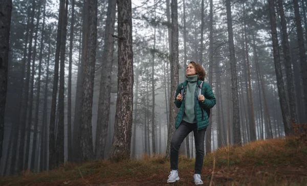 Jonge Vrolijke Vrouw Reiziger Groene Jas Met Rugzak Mistige Dennenbos — Stockfoto