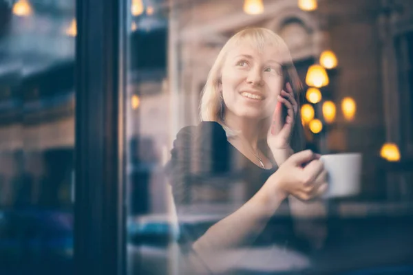 Красивая Молодая Блондинка Сидит Кафе Разговаривает Мобильному Телефону Окна Отражением — стоковое фото