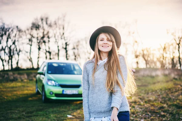 कार शेतात प्रवास करणार्या टोपीमध्ये एक सुंदर तरुण स्त्रीचे पोर्ट्रेट, स्वातंत्र्य साहसी रस्ता ट्रिप संकल्पना — स्टॉक फोटो, इमेज