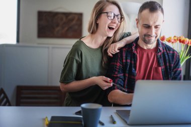 Güzel yetişkin bir çift dizüstü bilgisayarın önünde oturmuş internette sohbet ediyorlar.