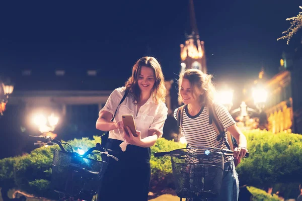 Two Friends Happy Smiling Young Women Walking Bicycles Night European — Stock Photo, Image