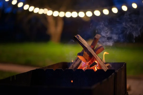 Drewniane Kłody Płonące Grillu Ogrodzie Nocnym Ozdobione Latarniami Kocepcja Imprez — Zdjęcie stockowe