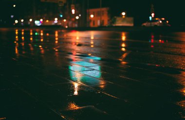 Gece yağmurdan sonra şehirde ıslak kaldırım yansıyan yol parlaklığı, soyut kentsel arka plan
