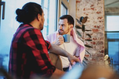 Evde oturup çay içen iki genç erkek arkadaş.