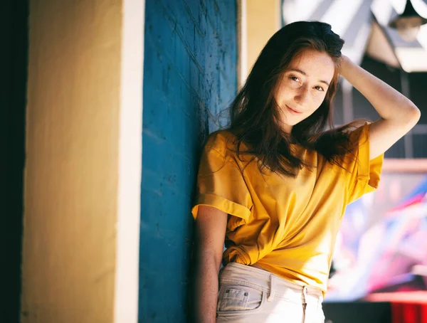 Portret Młodej Szczęśliwej Brunetki Żółtej Koszulce Koło Niebieskiej Ściany Mieście — Zdjęcie stockowe