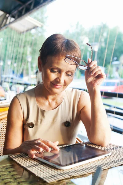 Mulher atraente de 50 anos com o tablet no café — Fotografia de Stock