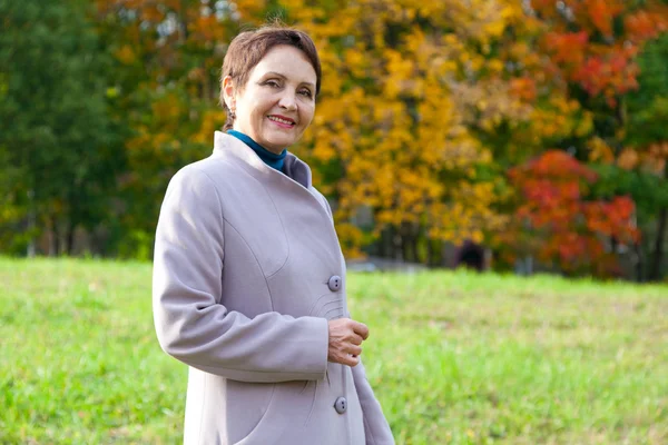 Atractiva mujer 50 años en el parque de otoño —  Fotos de Stock