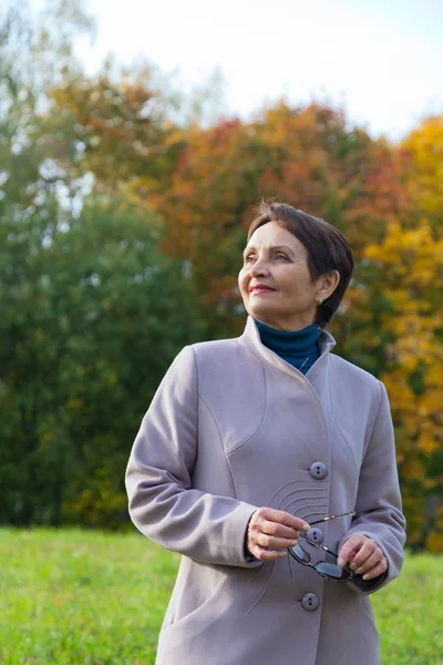 Attractive woman 50 years in the autumn park — Stock Photo, Image