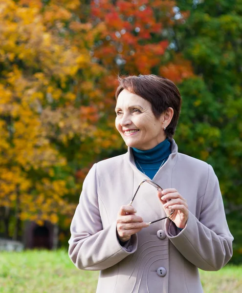 Mulher atraente 50 anos no parque de outono — Fotografia de Stock