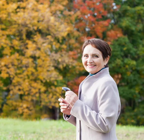 Attractive woman 50 years in the autumn park — Stock Photo, Image