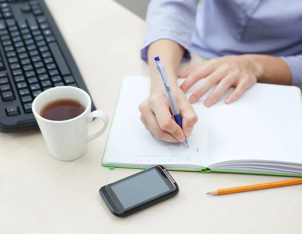 Gros plan des mains féminines prenant des notes dans le bloc-notes — Photo