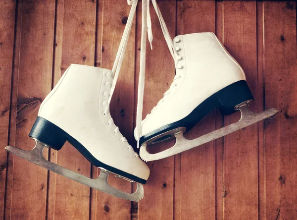 Patins de gelo brancos para patinação artística, pendurados em um backgro de madeira — Fotografia de Stock