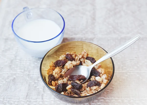 muesli with dried fruit in a bowl and glass of milk