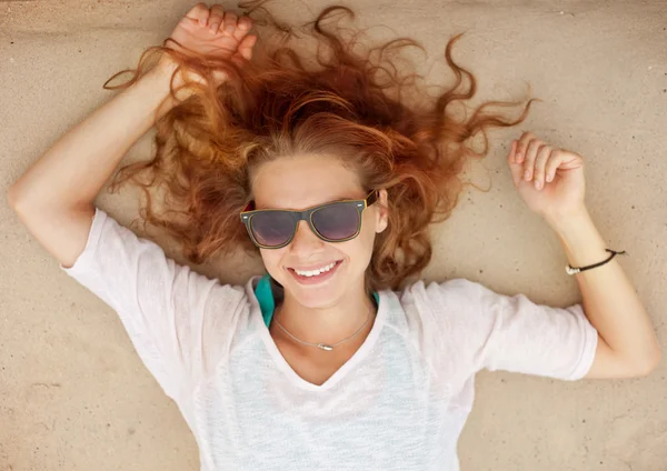 Schöne junge Frau mit Sonnenbrille im Sand liegend — Stockfoto