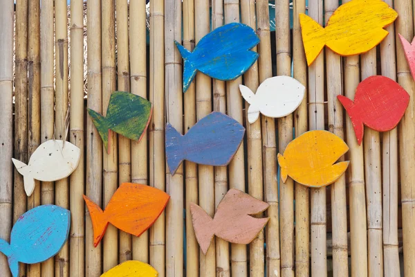 Bunte Holzfische auf der Bambusoberfläche, Meereshintergrund — Stockfoto