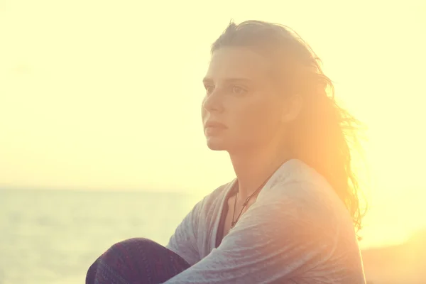 Portret van een mooie jonge vrouw bij zonsondergang op het strand — Stockfoto