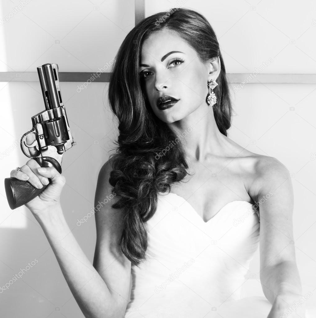 beautiful girl in a wedding dress with a gun, studio shooting