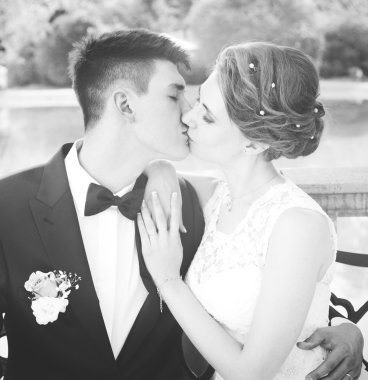 Çekici gelin ve damat öpüşme, bir bankta oturan