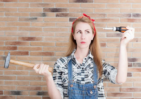 Attractive young woman with a hammer and a screwdriver, and on t — Stock Photo, Image