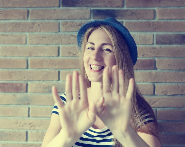 Divertente giovane donna con bretelle sui denti sul muro di mattoni backgro — Foto Stock