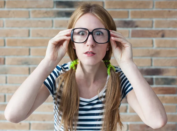 Divertente giovane donna con bretelle sui denti sul muro di mattoni bac — Foto Stock