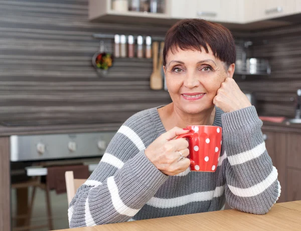 50 anos de idade mulher atraente com uma xícara de chá em casa — Fotografia de Stock