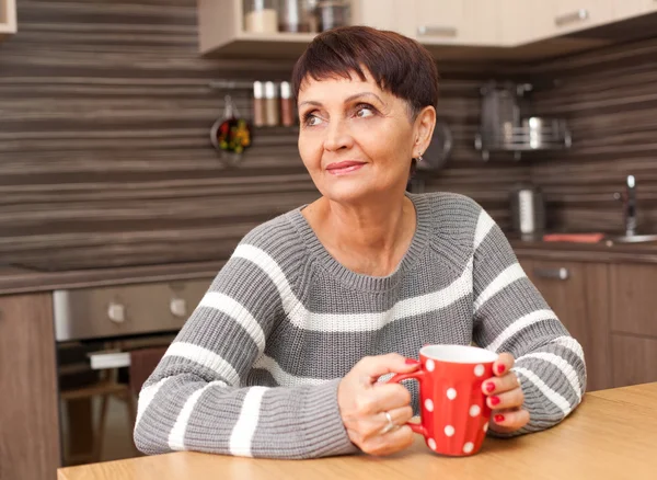 50 anos de idade mulher atraente com uma xícara de chá em casa — Fotografia de Stock