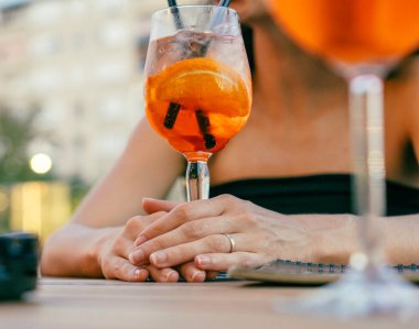 Dostça bir toplantı sırasında aperatif bardağı tutan kadın eli.