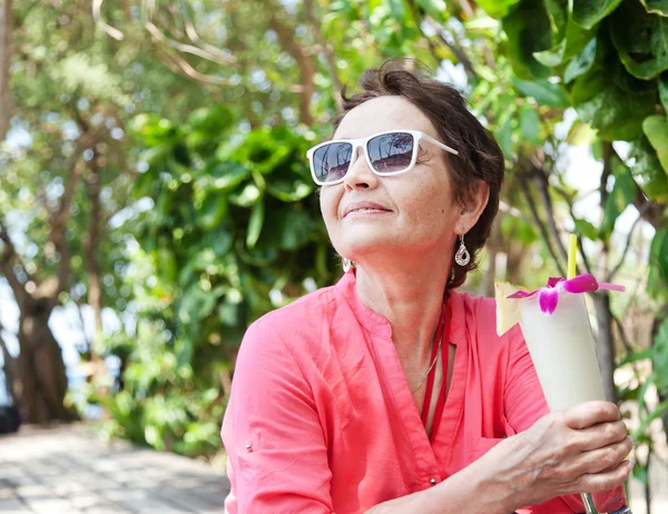 Beautiful elderly woman in a hat with a cocktail in hand. Summer — Stock Photo, Image