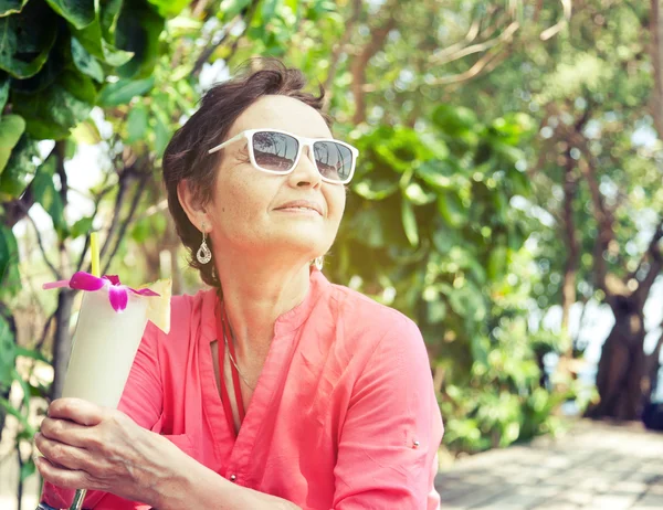 Beautiful elderly woman in a hat with a cocktail in hand. Summer — Stock Photo, Image