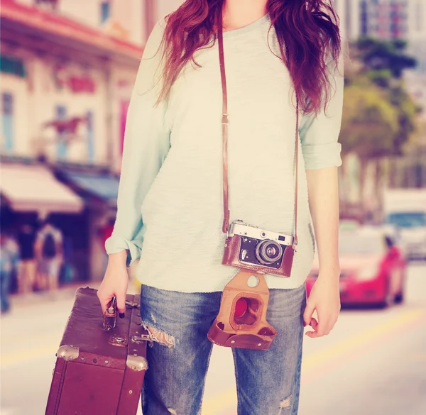 Mujer joven con maleta retro y cámara en el fondo de la ciudad —  Fotos de Stock