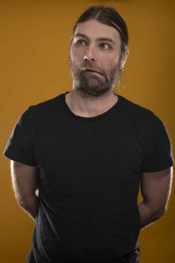 Uzun saçlı bir erkek kameraya hoş suratlar yapıyor.