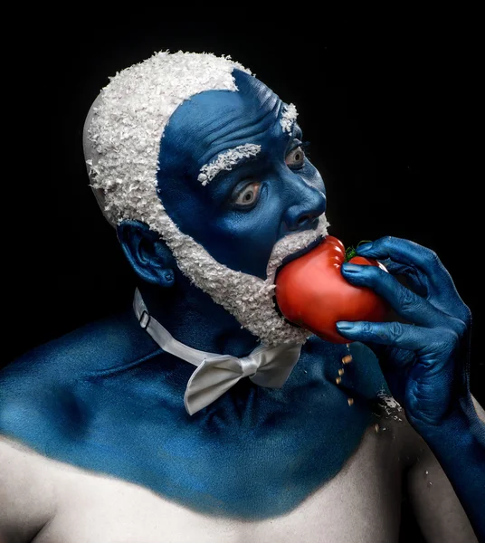 Man painted in blue color   eating tomato — Stock Photo, Image