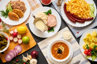 Tahta masadaki farklı yemek ve diğer malzemelerin üst görüntüsü.