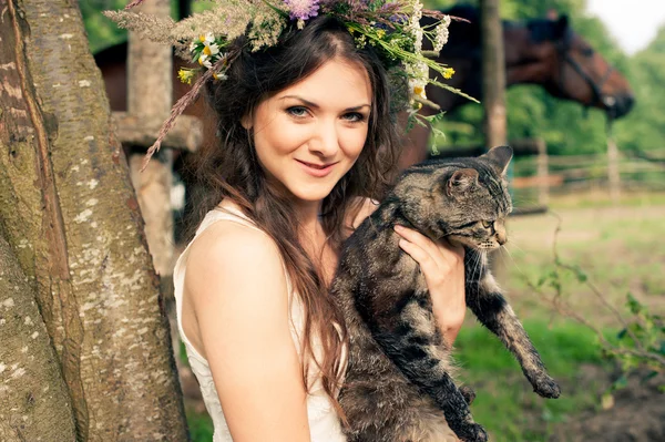 Güzel bir kadın çiçek çelenk ile kedi içinde — Stok fotoğraf