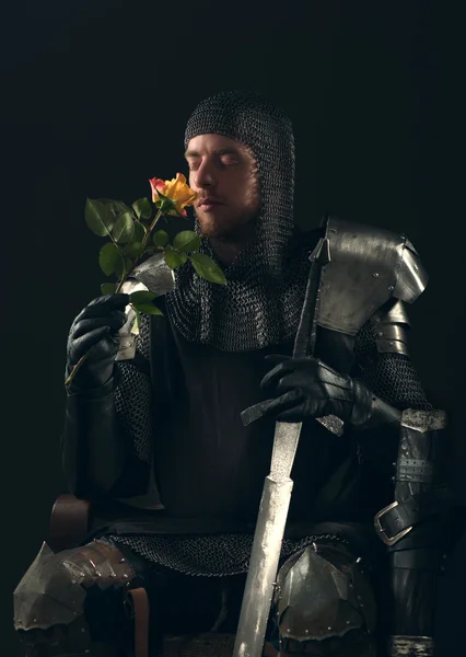 Ancient knight smelling yellow rose — Stock Photo, Image