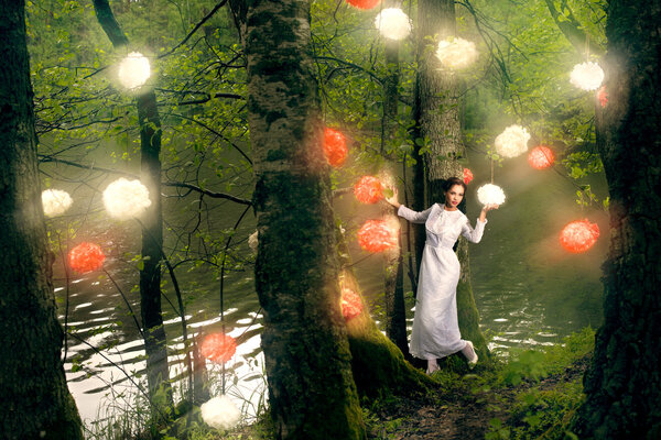 Young woman in white dress walking in the fairy forest with lighting decor